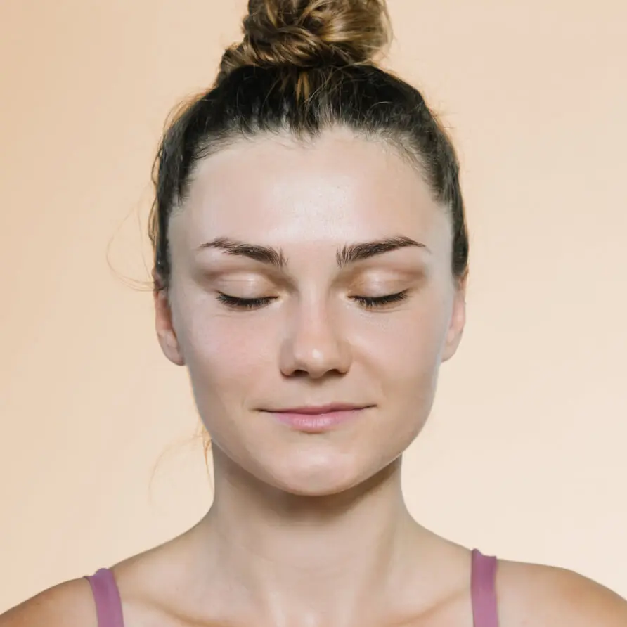 Junge Frau mit Dutt meditiert mit geschlossenen Augen